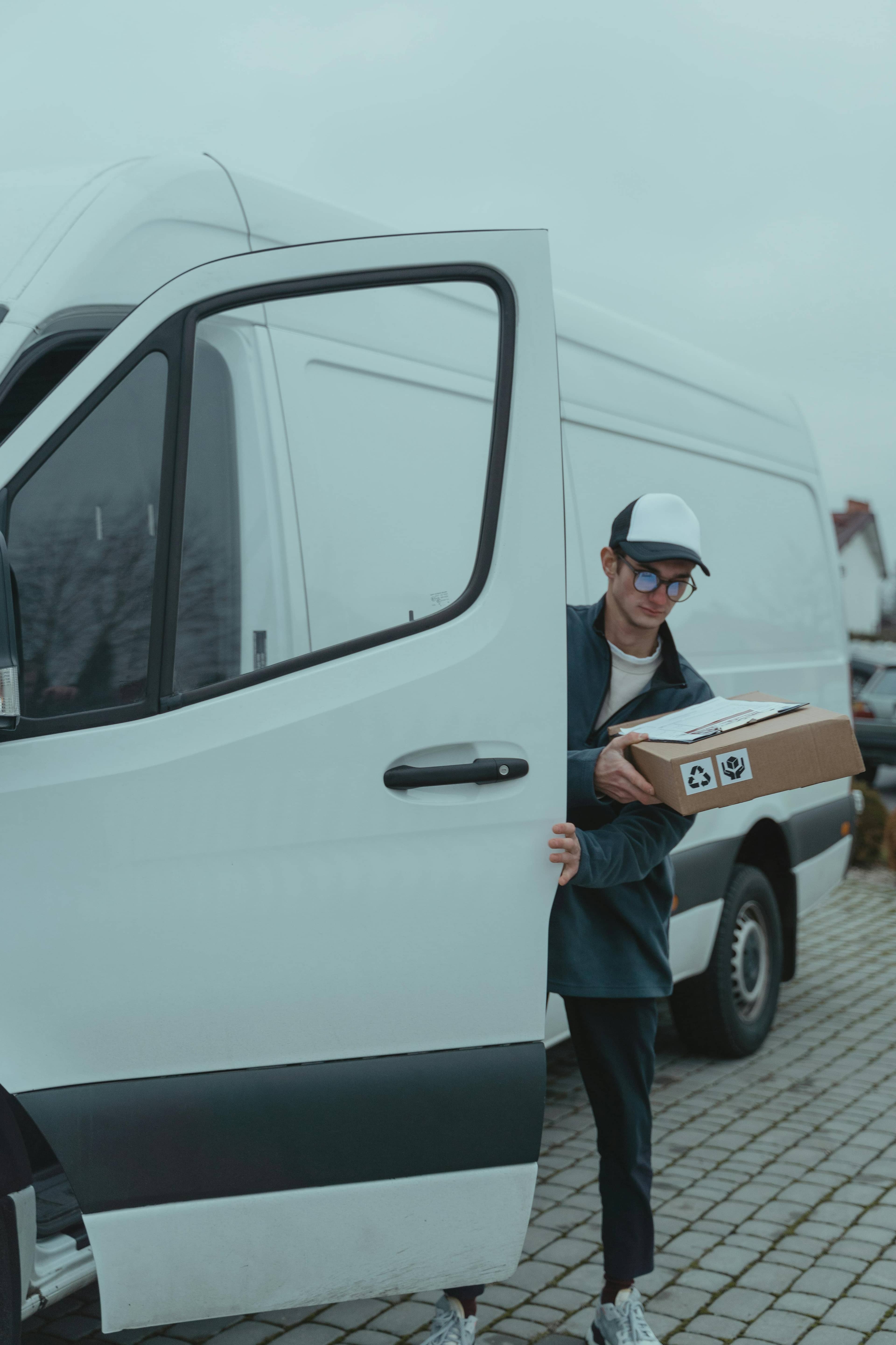 A courier carrying a parcel to a delivery van