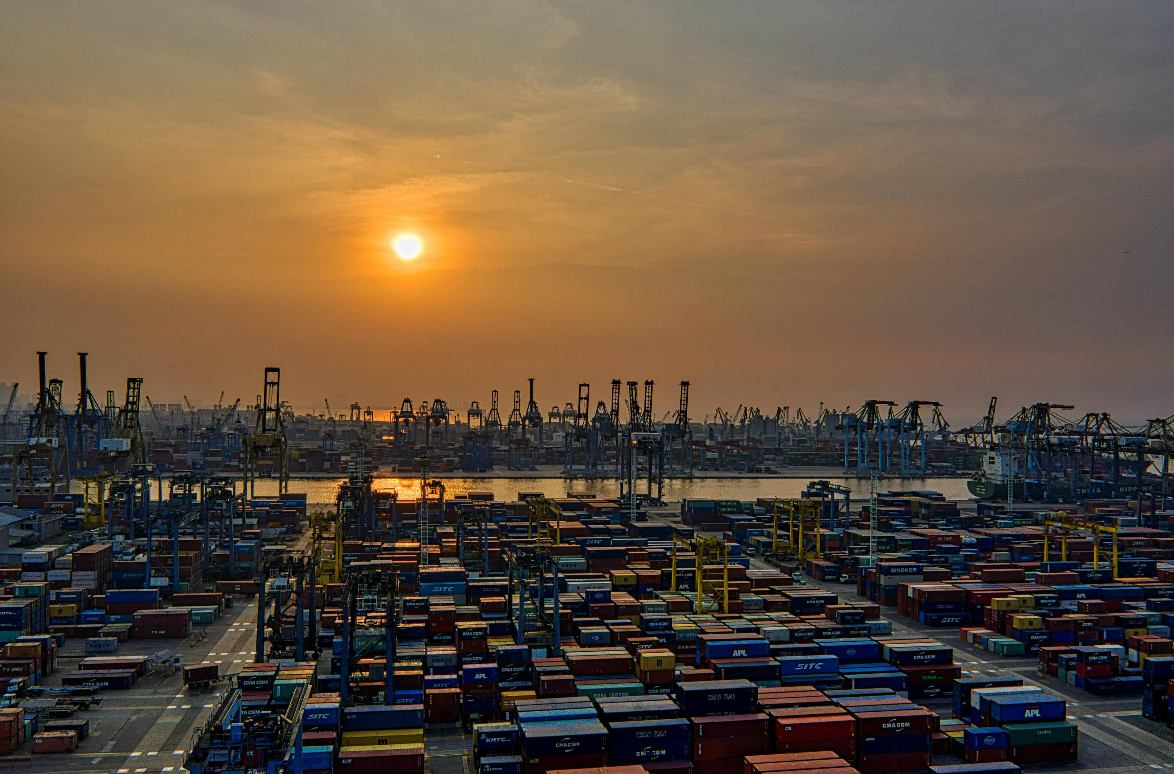 A container terminal at sunrise with cranes along the quay