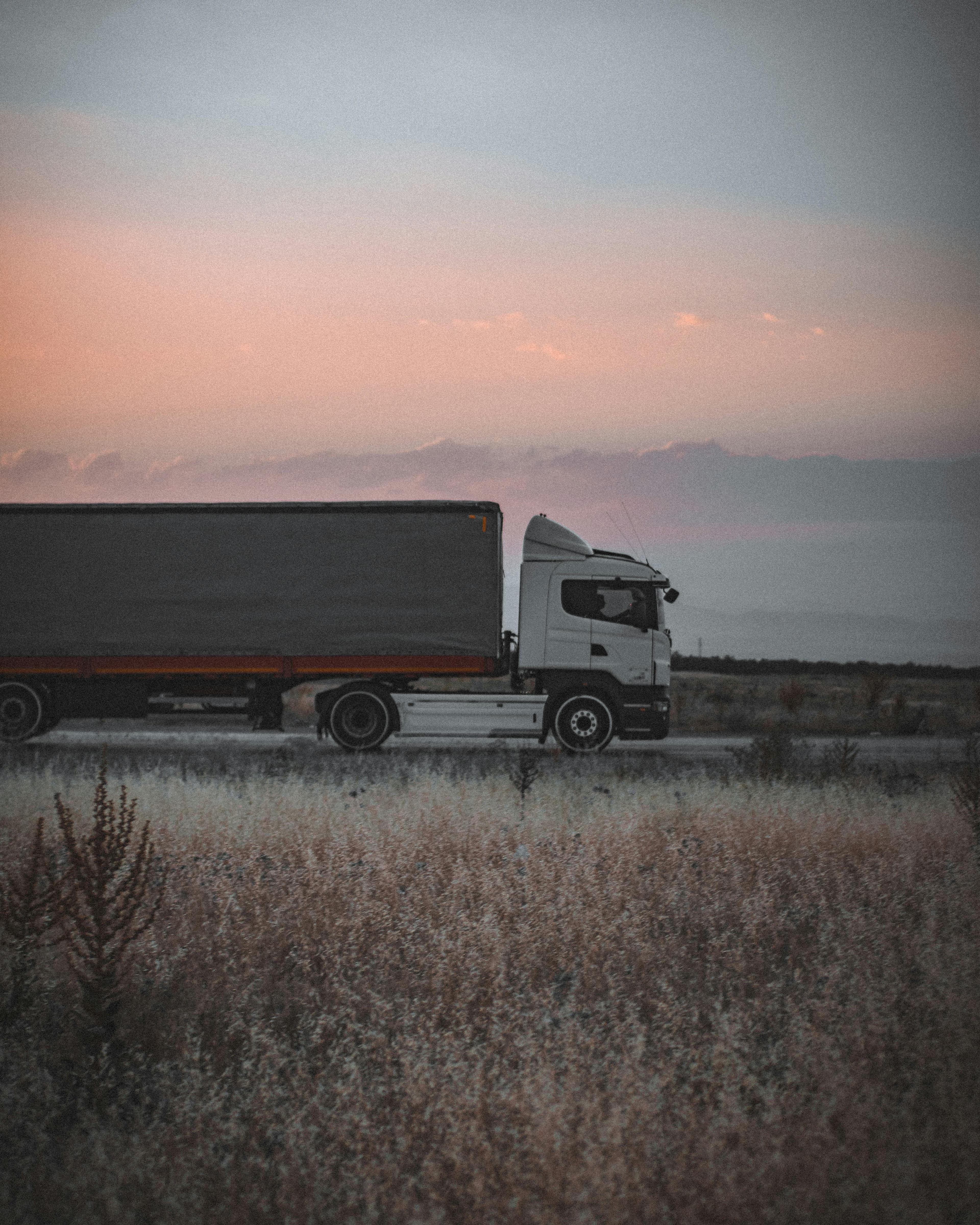 A tractor-trailer on an open road at dusk
